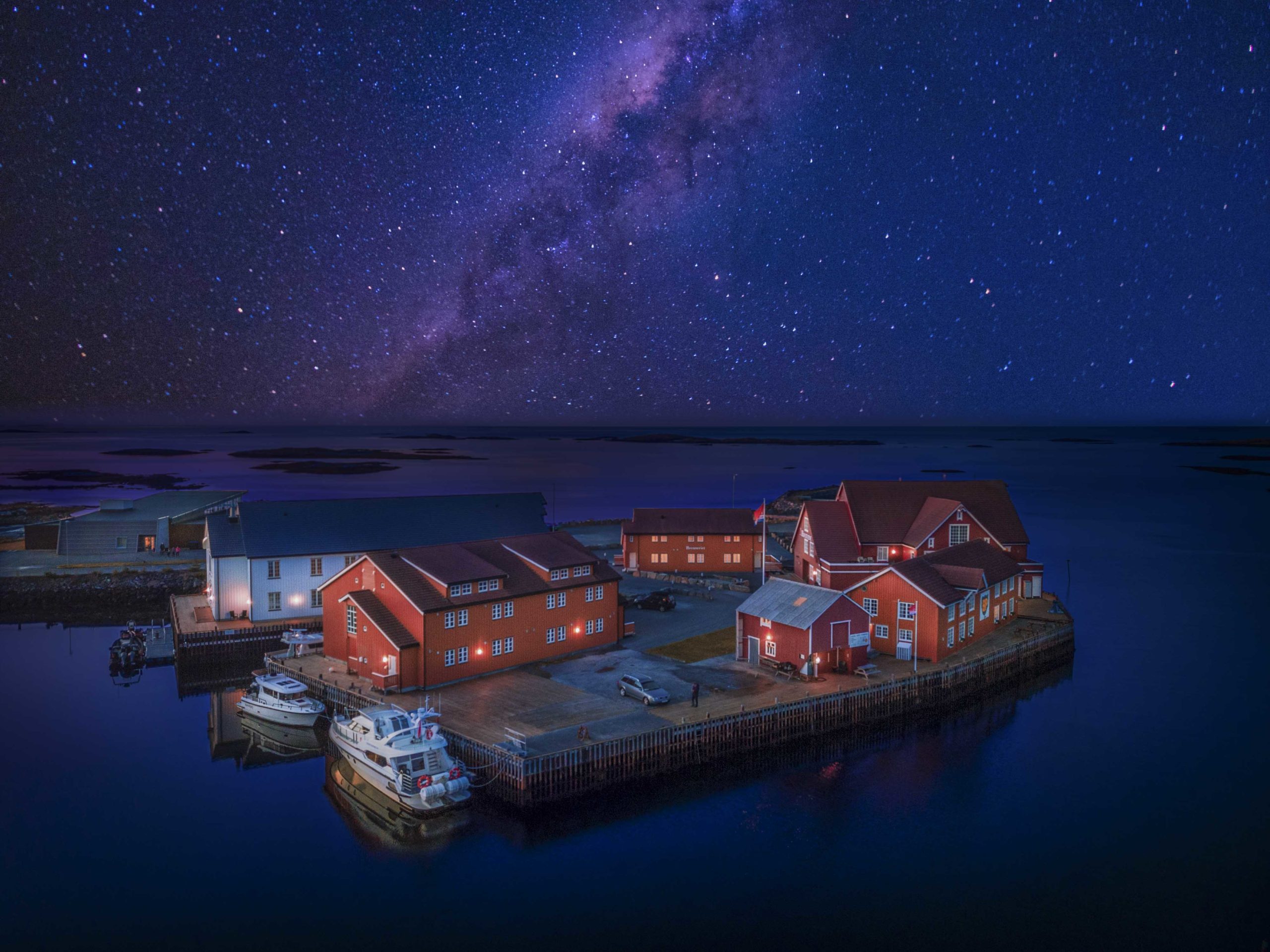 The hotel’s historic sea houses glow under a sky full of stars – a peaceful night by the open sea at Finnøy Bryggehotell.