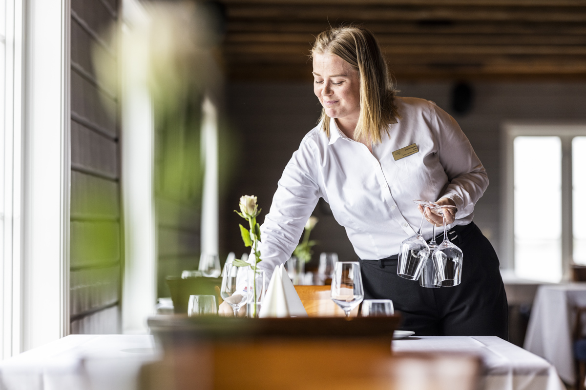 Servitør dekker bordet i Restaurant Sjøhuset