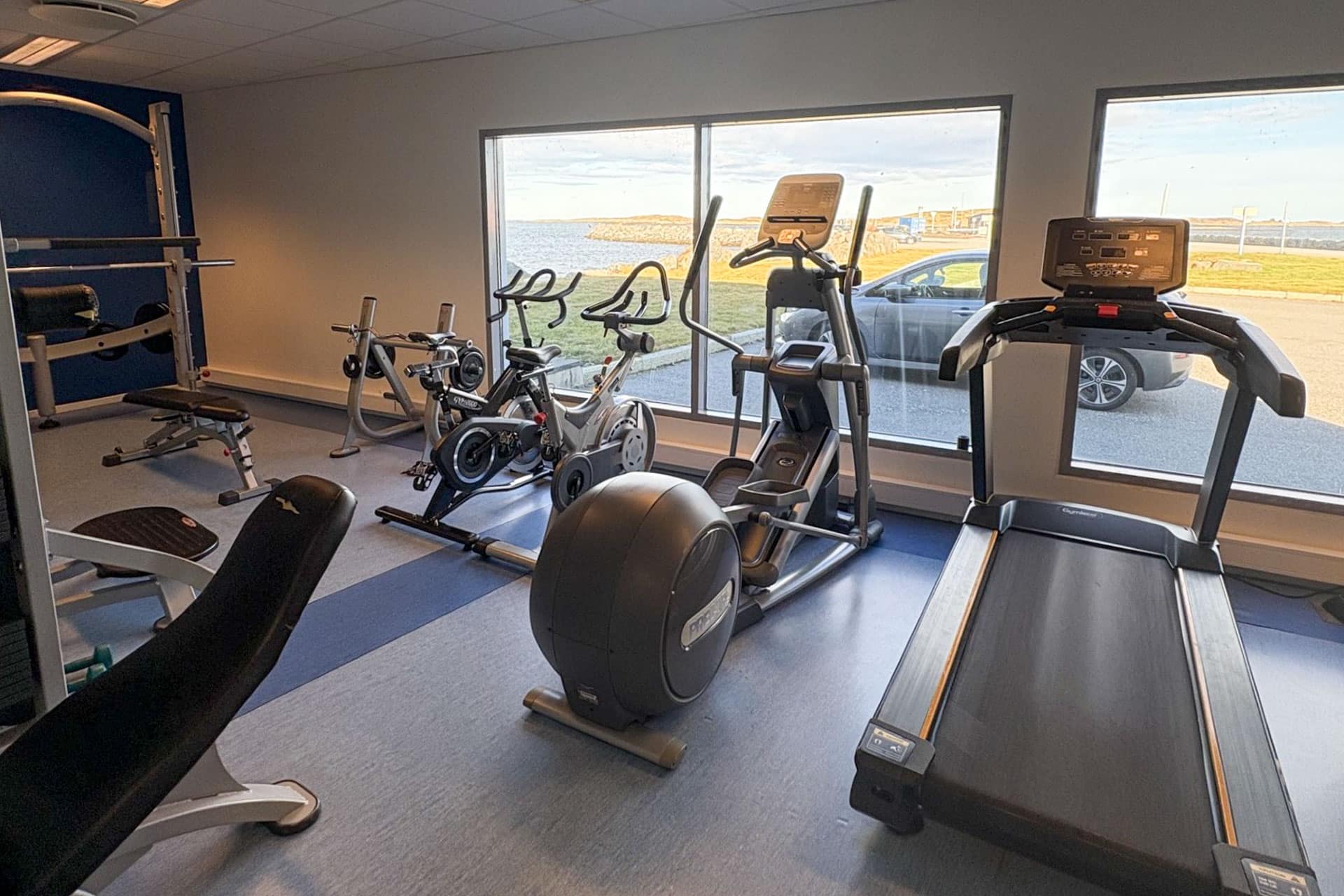 Fitness room with treadmill, exercise bikes and large windows on Finnøya.
